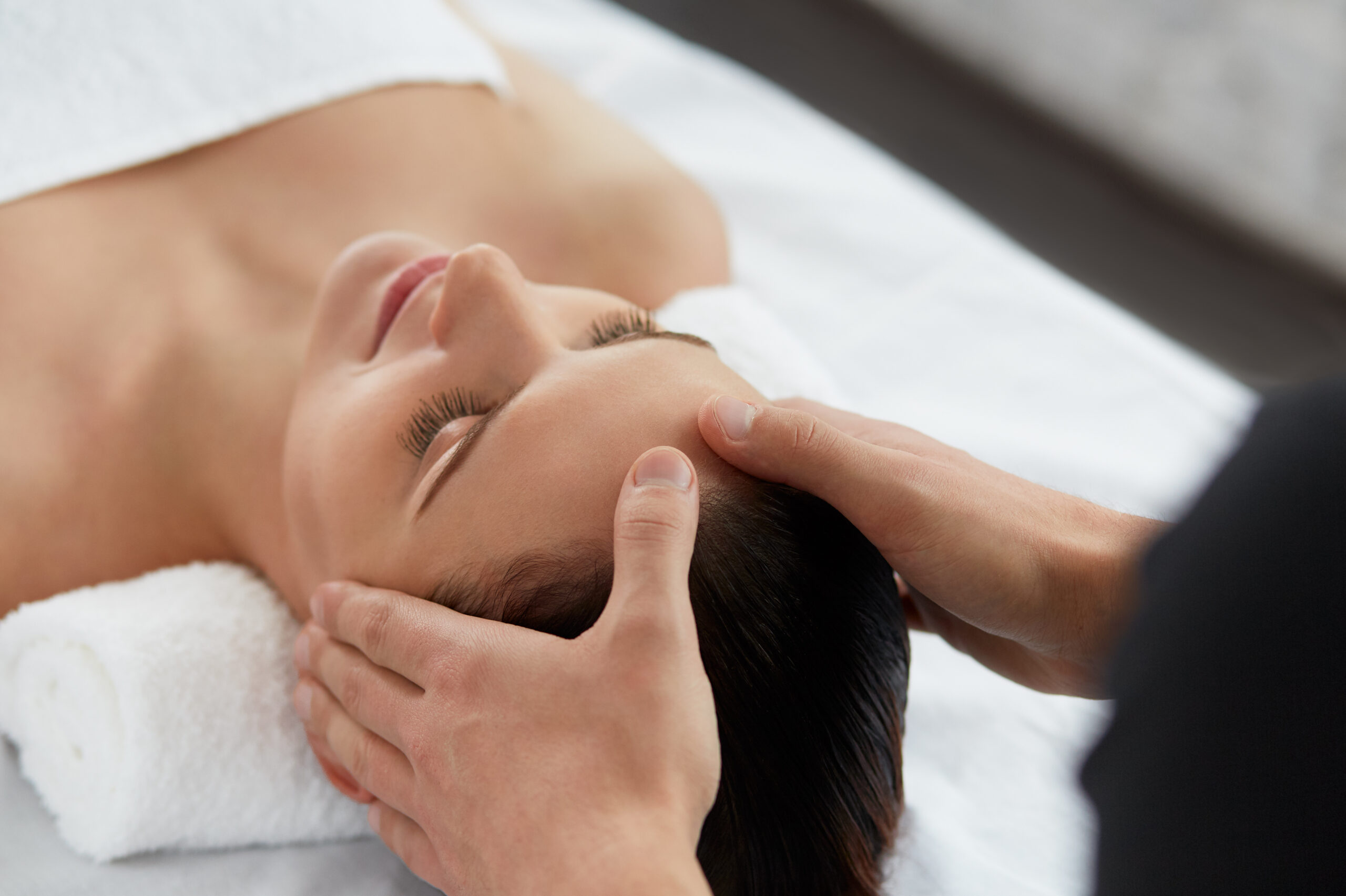 Young beautiful woman enjoying anti-aging facial massage.Male therapist making head massage to female client.Professional masseur.Relaxation,beauty,spa,body and face treatment concept.